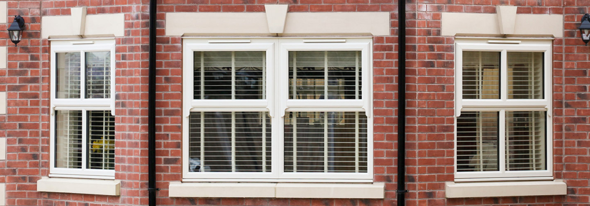 White uPVC windows with glazing bars and a brick surround